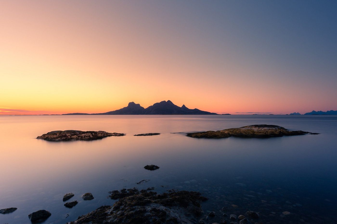 Solnedgang over havet med en øy i silhuett i horisonten