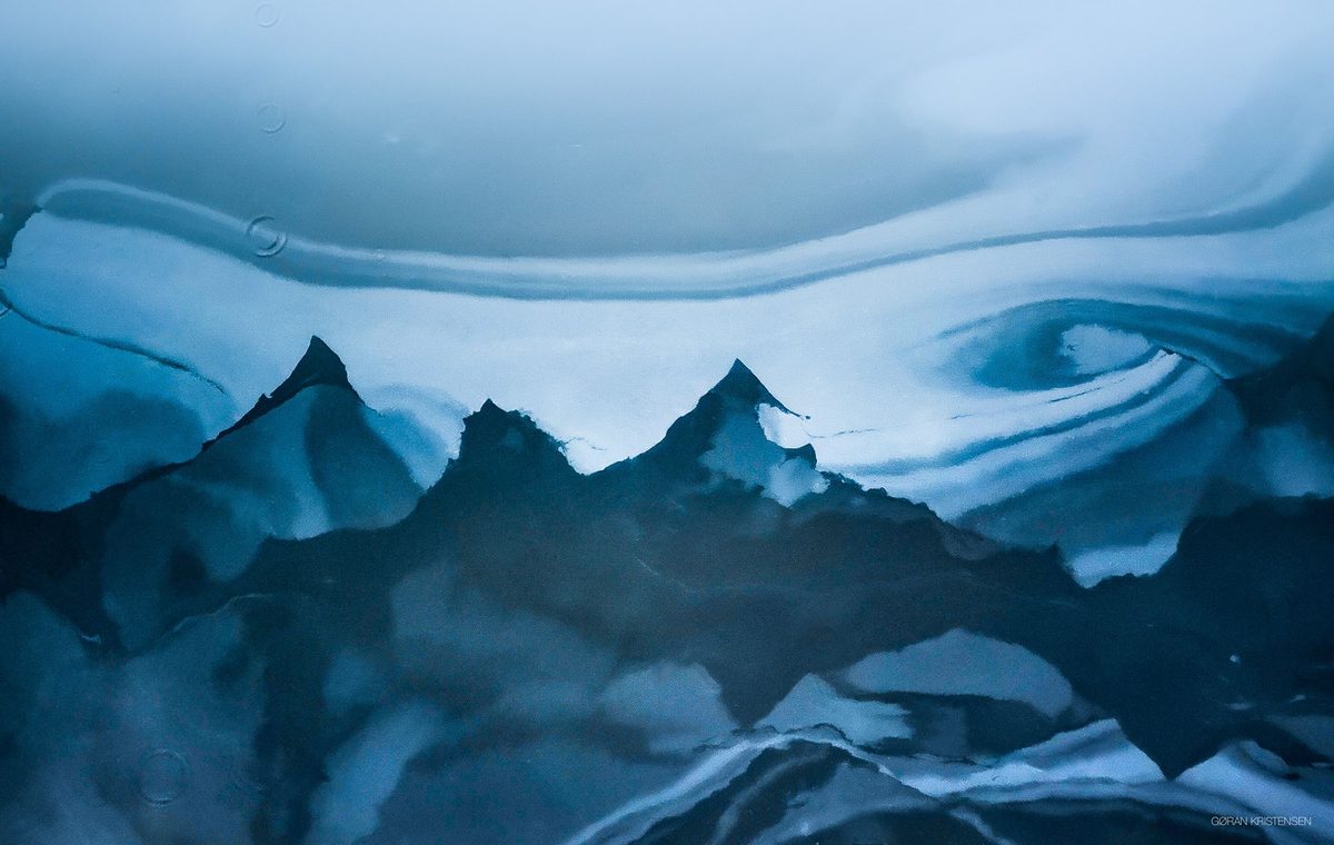 Abstrakt, blåtonet mønster som minner om fjelltopper, skapt av lys og struktur i vann